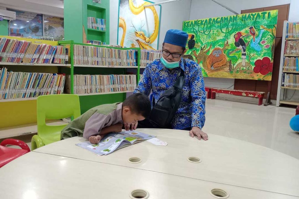 Irfan Jaya, kepala SDIT Imam Syafi'i nampak sedang mengajari salah satu siswanya saat berkunjung ke perpustakaan DPK Kaltim.