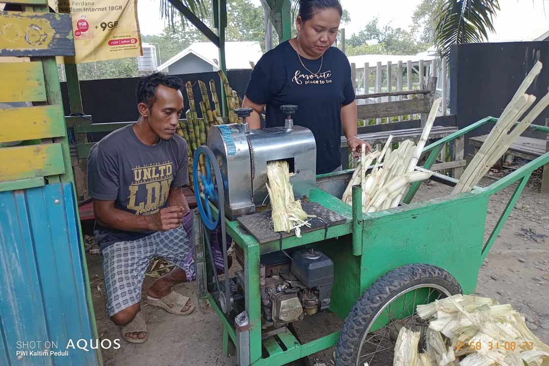Heni Misinem saat memeras tebu menggunakan mesin.